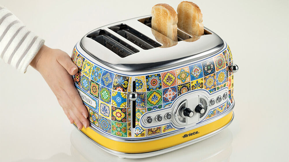 Toster Ariete 1560P zbliżenie na przyciski wzorzysta obudowa jasne tło osoba trzyma rękę na obudowie funkcja szybkiego rozmrażania i delikatnego podgrzewania pieczywa wygoda smak ulubionych przekąsek wzorzysty design łatwość obsługi partner w codziennym przygotowywaniu posiłków System Cool Touch bezpieczeństwo użytkowania