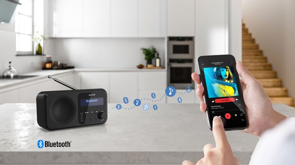 Radio SHARP DR-P421 Bluetooth bezprzewodowy głośnik smartfon tablet, radio stojące na kamiennym blacie, osoba trzymająca smartfon w ręku