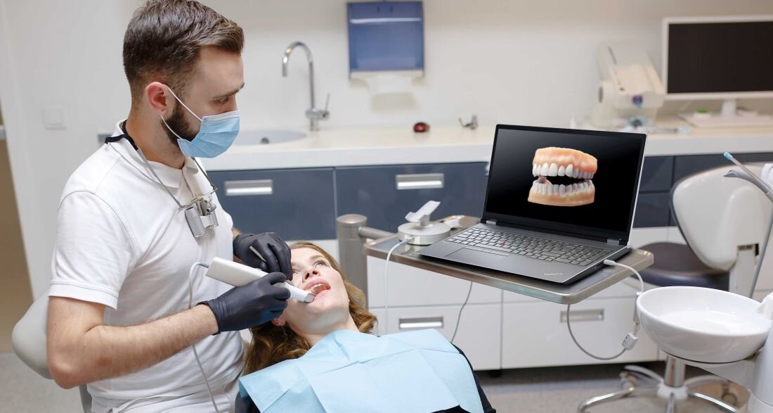 Dentysta wykonujący zabieg z laptopem Lenovo ThinkPad P16 wyświetlającym model 3D uzębienia w gabinecie stomatologicznym - zasłonka ochronna kamery