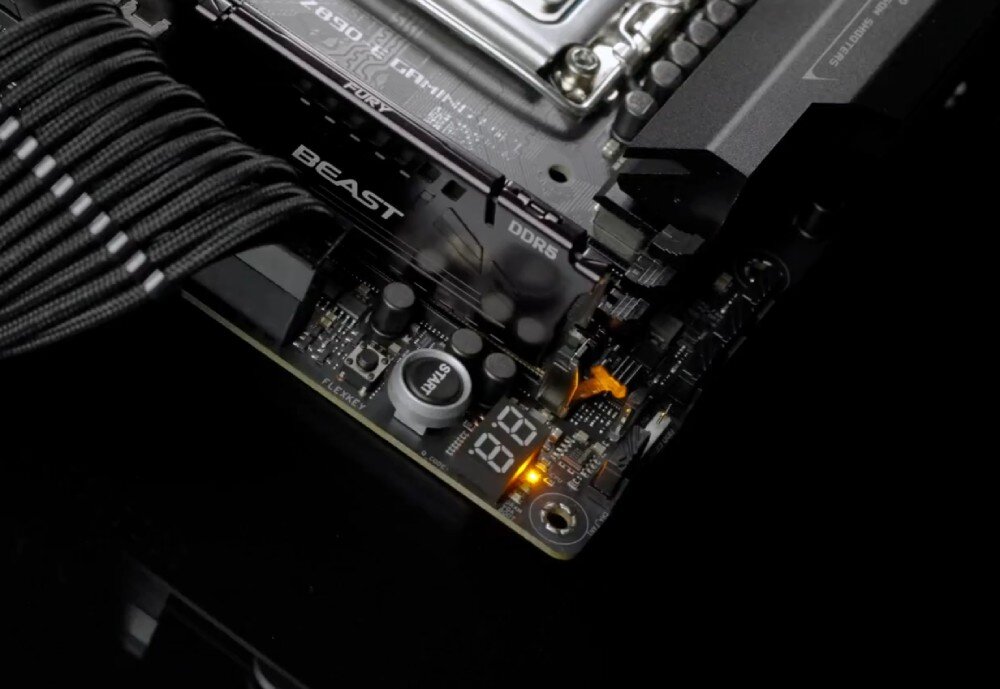 Płyta główna ASUS ROG Strix Z890-E Gaming WiFi zbliżenie na przycisk 'START', złącze zasilania i wyświetlacz diagnostyczny Q-Code świecący na pomarańczowo obok zamontowanej pamięci DDR5, ułatwienia montażu, rozwiązania