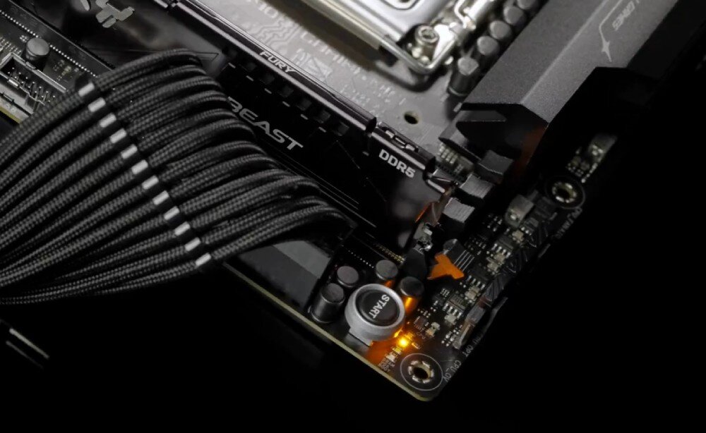 Płyta główna ASUS ROG Strix Z890-F Gaming WiFi Zbliżenie na fragment płyty głównej z czarnymi przewodami w oplocie, modułem pamięci DDR5 i świecącą na pomarańczowo diodą diagnostyczną, montaż, rozwiązania