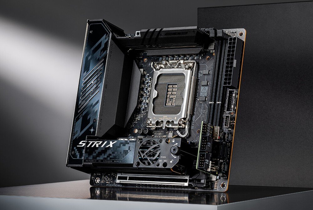 Płyta główna ASUS ROG Strix Z890-I Gaming WiFi Płyta główna mini-ITX ustawiona pod kątem na metalowej powierzchni z widocznym gniazdem procesora, radiatorami i wentylatorem sekcji zasilania, format, wielkość, kompatybilne procesory