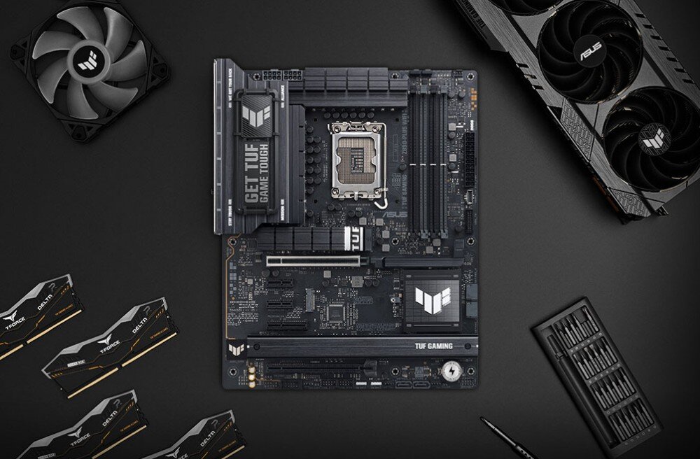 Płyta główna ASUS TUF Gaming Z890-PLUS WiFi Płaska kompozycja płyty na biurku otoczonej modułami DDR5, kartą graficzną, wentylatorem i zestawem narzędzi, interfejsy, metalowa osłona