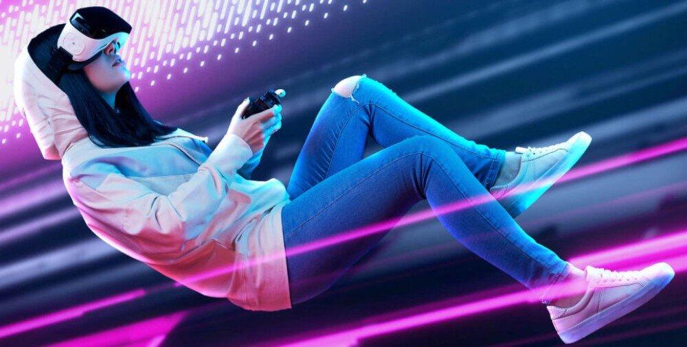 Płyta główna GIGABYTE Z890 Eagle WiFi7 Osoba w jasnej bluzie i goglach VR trzymająca kontroler, unosząca się w przestrzeni na tle dynamicznego, kolorowego tła, łączność, gniazdo PCIe, łączność Wi-Fi