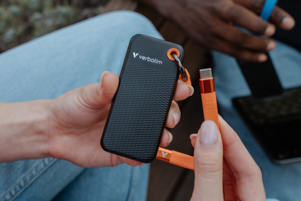 Dysk VERBATIM Pocket 2TB SSD Czarno-pomarańczowy zbliżenie na dysk oraz złącze kabla, który jest podłączony z jednej strony do dysku interfejs prędkość podłączenie kabel kompatybilność