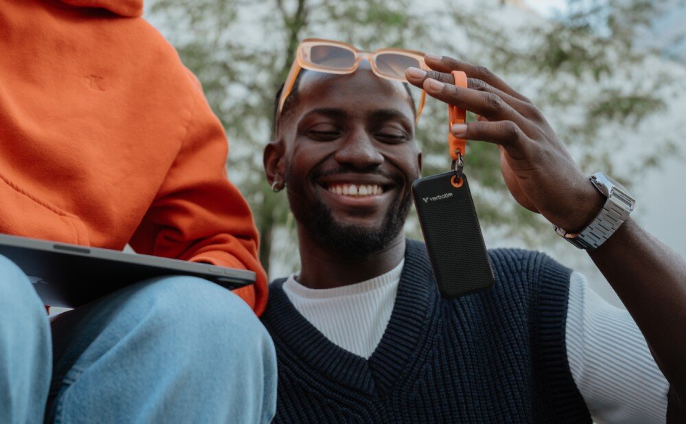 Dysk VERBATIM Pocket 2TB SSD Czarno-pomarańczowy osoba trzymająca brelok, do którego przymocowany jest dysk technologia SSD wytrzymałość zalety