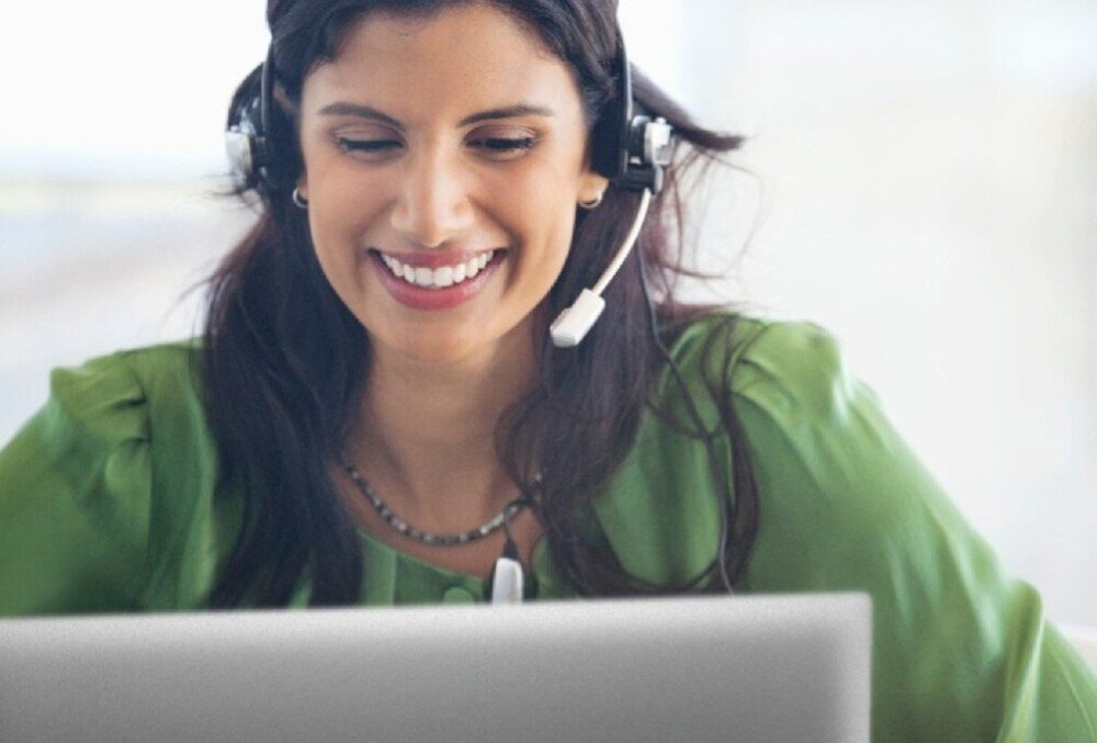 Laptop DELL Latitude 7340 Kobieta w zielonej bluzce z zestawem słuchawkowym patrzy na ekran laptopa i się uśmiecha, bezpieczeństwo, czytnik linii papilarnych