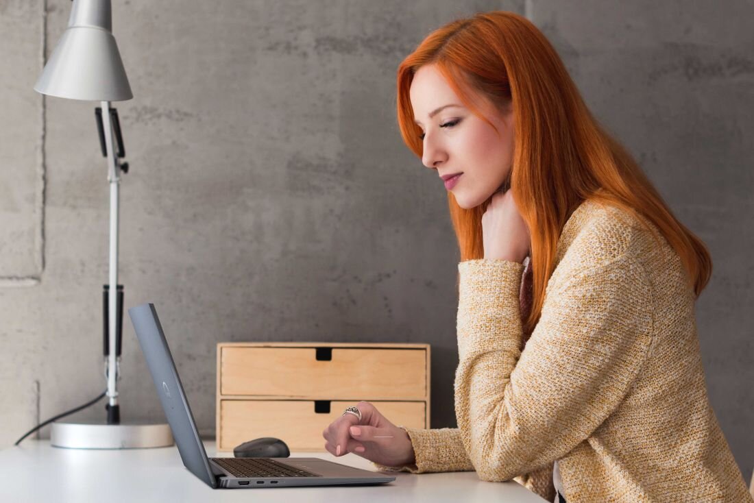 Kobieta z rudymi włosami siedzi przy biurku, korzystając z laptopa DELL Latitude 7350.  - błyskawiczny dostęp Copilot
