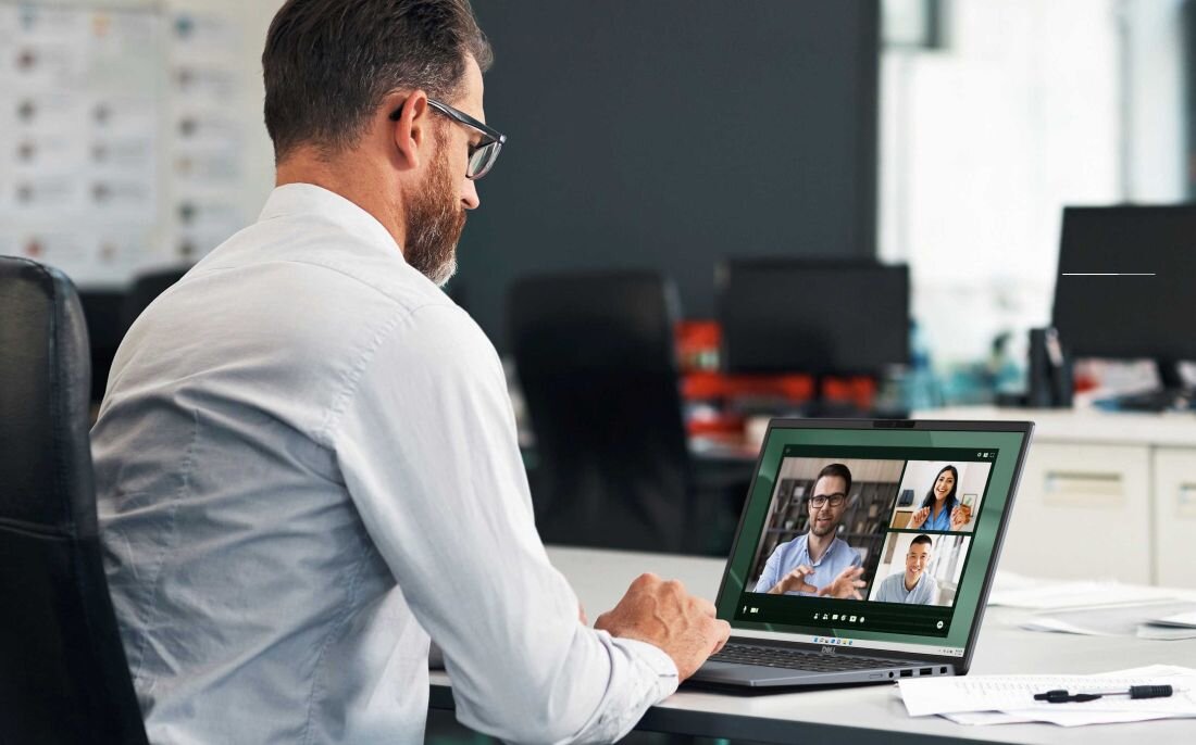 Mężczyzna siedzi przy biurku z laptopem DELL Latitude 7450, prowadząc rozmowę wideo na ekranie.  - zaawansowana łączność Wi-Fi 7 Bluetooth 5.4