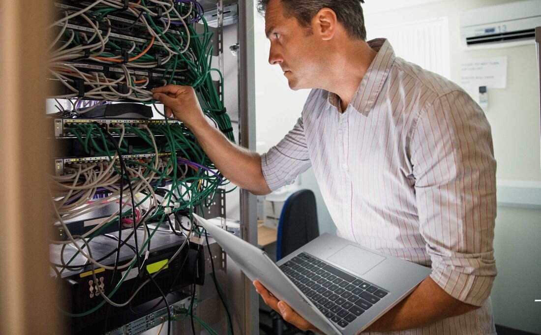 Mężczyzna pracuje na laptopie DELL Latitude 5440 w serwerowni, otoczony przez rzędy serwerów. - Opis serii Latitude 5450  
