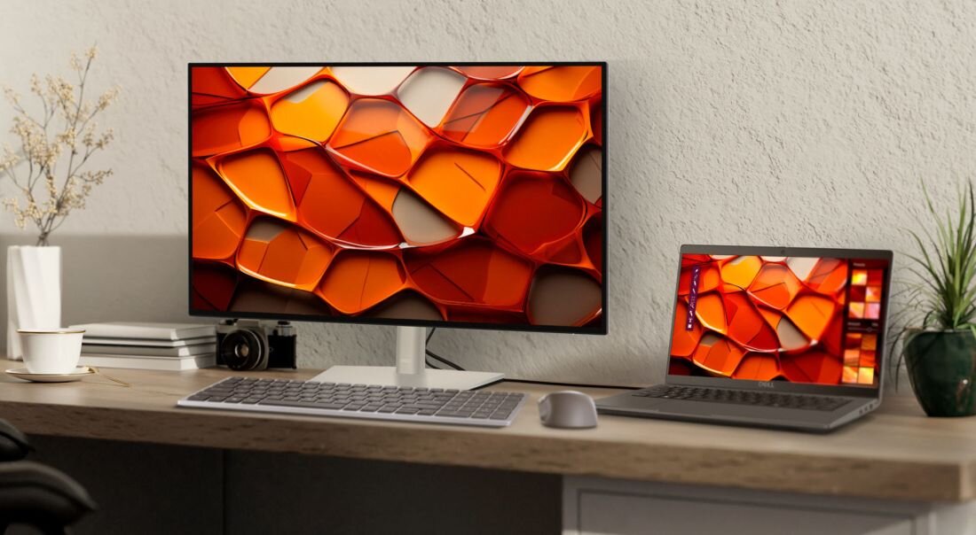 Domowe biurko z dużym monitorem DELL podłączonym do laptopa DELL Latitude, oba wyświetlające tę samą pomarańczową grafikę w trybie rozszerzonego ekranu obok klawiatury i myszy. - 14-calowy ekran Full HD  
