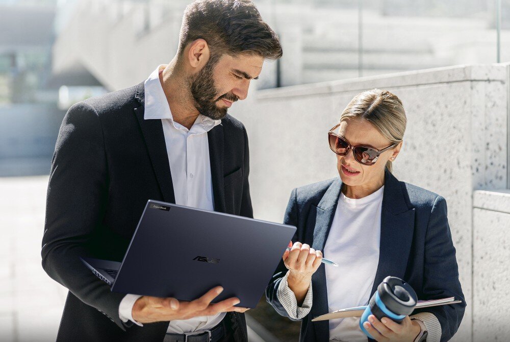 Laptop ASUS ExpertBook B5404CMA-Q50339X Mężczyzna i kobieta w formalnych strojach stoją na zewnątrz budynku i wspólnie patrzą na ekran laptopa, łączność Wi-Fi 6E, port LAN