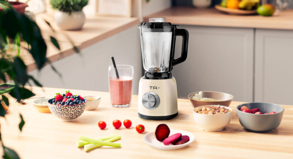 Blender kielichowy ETA Storio 901190010 Beżowy do koktajli beżowy blender stoi na blacie srebrne pokrętło czarna rączka kielich obok składniki w miseczkach 