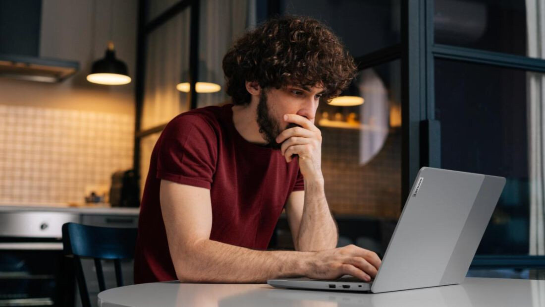 Mężczyzna siedzi przy stole, korzystając z laptopa IdeaPad Slim 3 Chrome.