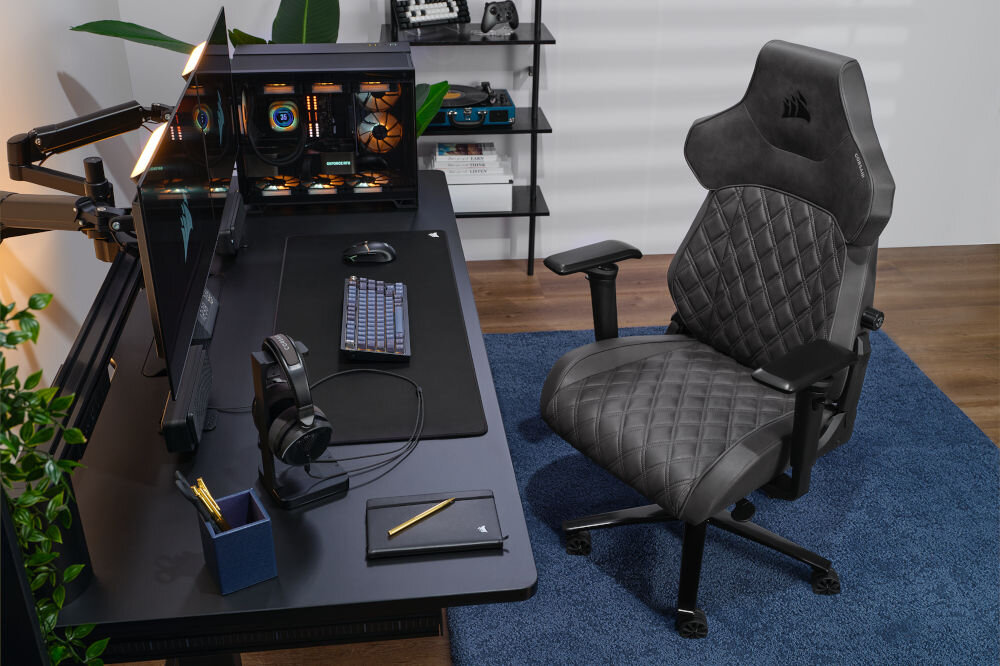 FOTEL CORSAIR TC500 Luxe - SHADOW GRAFITOWY stojący przy biurku wyposażonym w słuchawki, klawiaturę, myszkę, głośniki, monitor oraz komputer