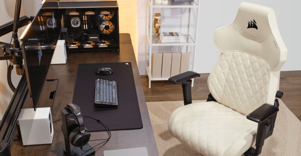 FOTEL CORSAIR TC500 Luxe - FROST KREMOWY stojący przy biurku wyposażonym w słuchawki, klawiaturę, myszkę, głośniki, monitor oraz komputer