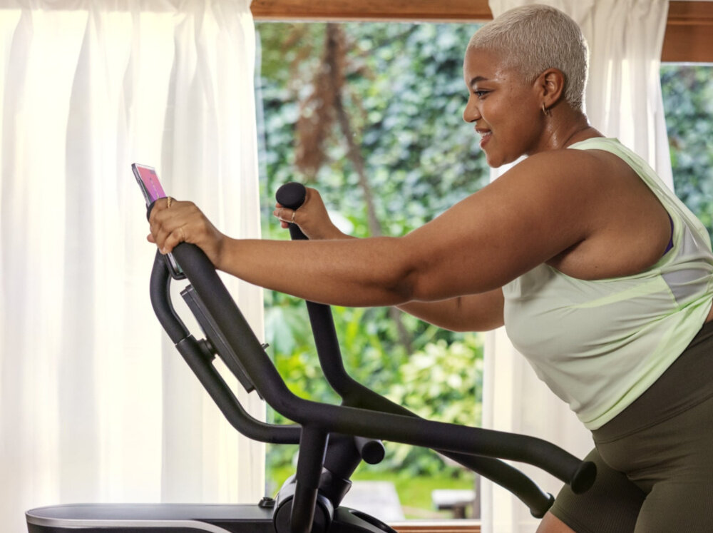 Orbitrek magnetyczny BOWFLEX SEi Max Trainer osoba trenuje na maszynie w pomieszczeniu zbliżenie na uchwyty poprawa kondcji spalanie kalorii wzmacnianie mięśni całego ciała płynna praca szeroki zakres oporu 