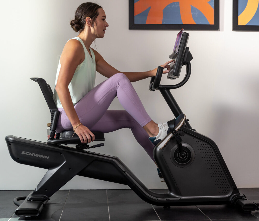 Rower magnetyczny SCHWINN R590 osoba siedzi na rowerze ćwicząć w pomieszczeniu komfortowy trening w domu wsparcie w treningu pozioma konstrukcja poprawa wydolności kondycja dbanie o zdrowie