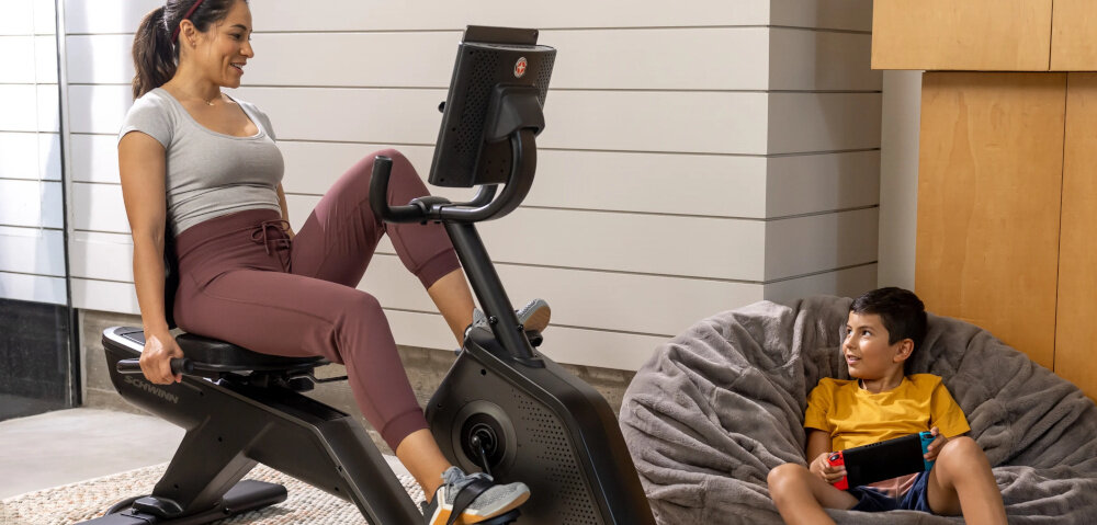 Rower magnetyczny SCHWINN R590 osoba siedzi na rowerze ćwicząć w pomieszczeniu dla osób dbających o kondycję i zdrowie intensywny trening bez wychodzenia z domu angażuje mięśnie nóg poprawa wydolności organizmu pozioma konstrukcja