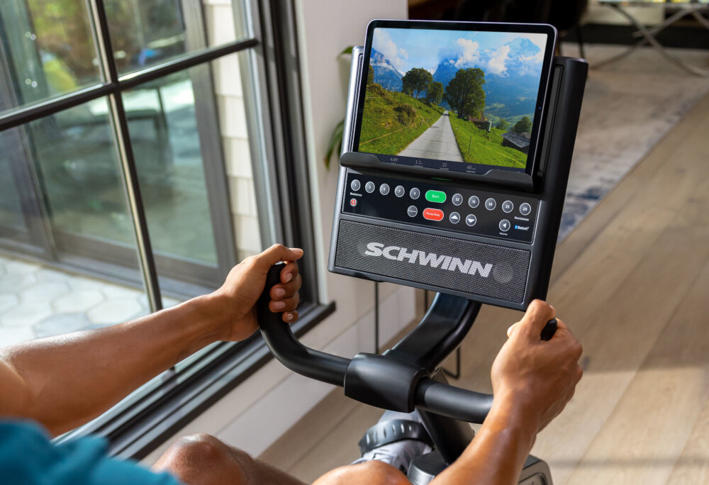 Rower magnetyczny SCHWINN R590 tablet umieszczomny na uchwycie z włączoną aplikacją moduł Bluetooth synchronizację danych treningowych z aplikacjami fitness 13 wgranych programów dostęp do ponad 1000 treningów w aplikacji JRNY dostęp do aplikacji Explore the World i Zwift aplikacje dostępne na systemy Android i iOS