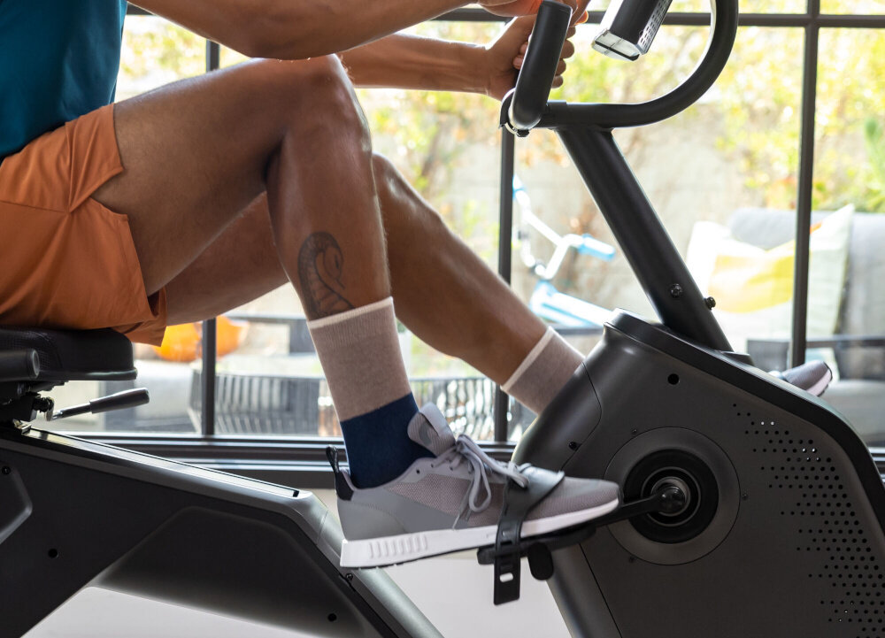 Rower magnetyczny SCHWINN R590 osoba siedzi na rowerze ćwicząć w pomieszczeniu zbliżenie na pedały pedały z regulowanymi paskami stabilizują stopę duża kontrola bezpieczeństwo obciążona konstrukcja płynne pedałowanie