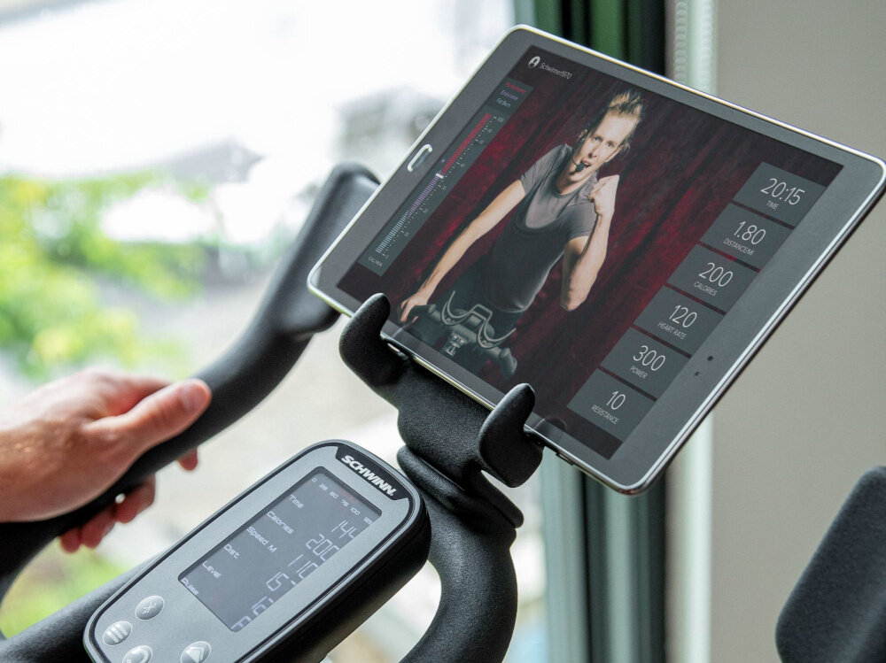 Rower spiningowy SCHWINN Indoor Cycling Schwinn 800IC zbliżenie na tablet z włączoną aplikacją technologia Bluetooth łączność z aplikacjami Zwift® i RideSocial® JRNY dostęp do wirtualnych tras uczestniczyć w wirtualnych zawodach dostęp do szerokiego katalogu treningów na żądanie