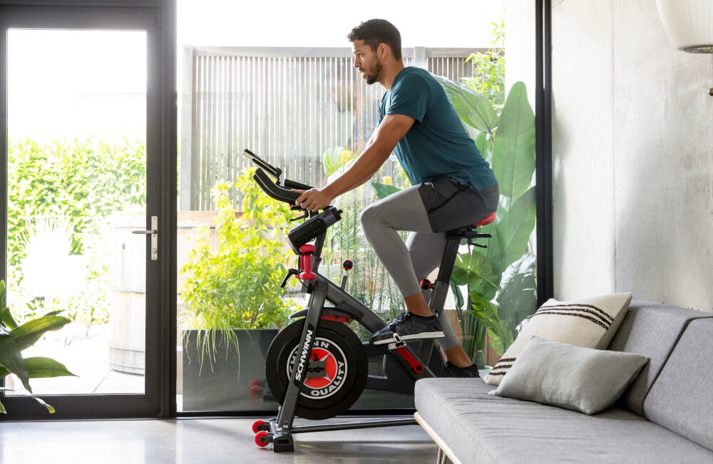 Rower spiningowy SCHWINN Indoor Cycling Schwinn 800IC osoba jedzie na rowerze w pomieszczeniu solidnie zbudowany waga koła zamachowego wynosi 18 kg długotrwała żywotność sprzętu