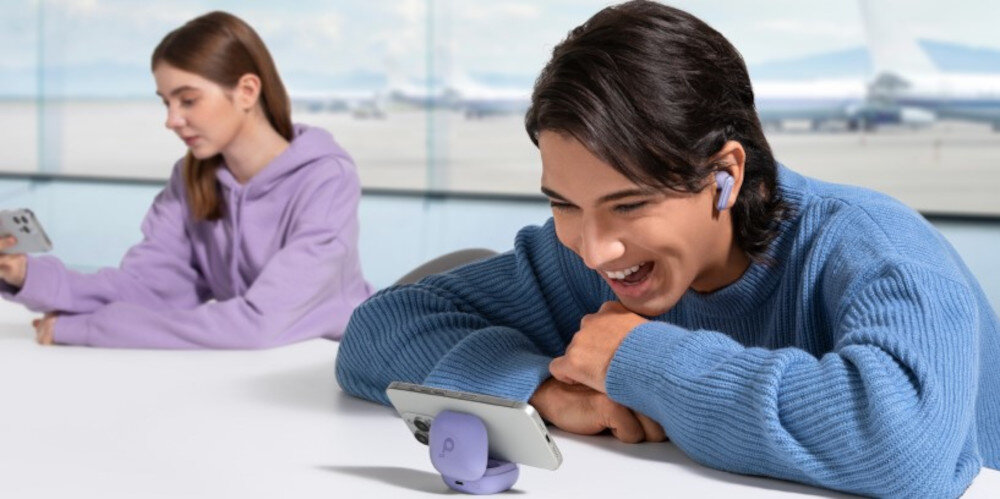 Słuchawki dokanałowe SOUNDCORE P40i ANC etui 2w1 stojak samozamykający, osoba z założonymi słuchawkami dokanałowymi wpatdzona w tleefon zamocowany na etui