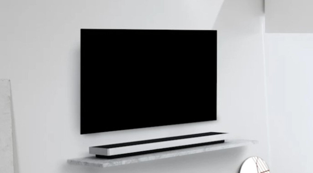 Soundbar BANG & OLUFSEN Beosound Stage - Wydajność bez subwoofera, soundbar położony na półce , telewizor zawieszony na ścianie