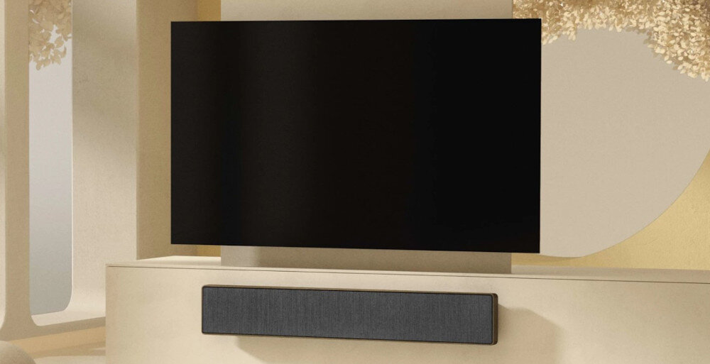 Soundbar BANG & OLUFSEN Beosound Stage - Bezprzewodowa łączność, telewizor zawieszony na ścianie z soundbarem w jasnym pomieszczeniu