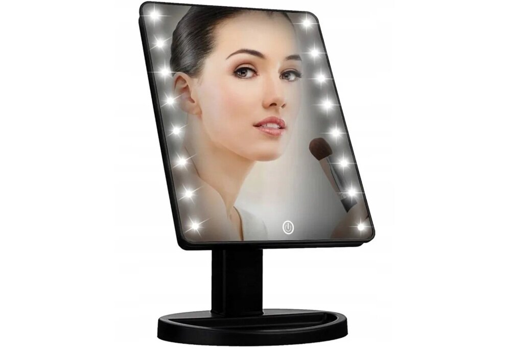 Lusterko kosmetyczne z oświetleniem LED wokół krawędzi, ustawione na czarnej podstawie. Na lusterku odbija się twarz osoby trzymającej pędzel do makijażu.