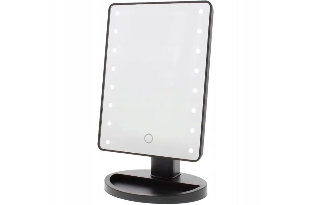 Na zdjęciu widoczne jest prostokątne lusterko kosmetyczne z oświetleniem LED wzdłuż krawędzi. Lusterko jest zamocowane na czarnej podstawie z miejscem na drobne przedmioty.