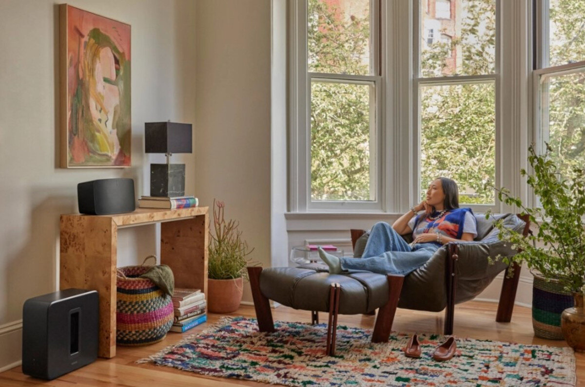 Subwoofer SONOS Sub 4 - Muzyka w innym brzmieniu, subwoofer stojący w salonie, kobieta siedząca na fotelu