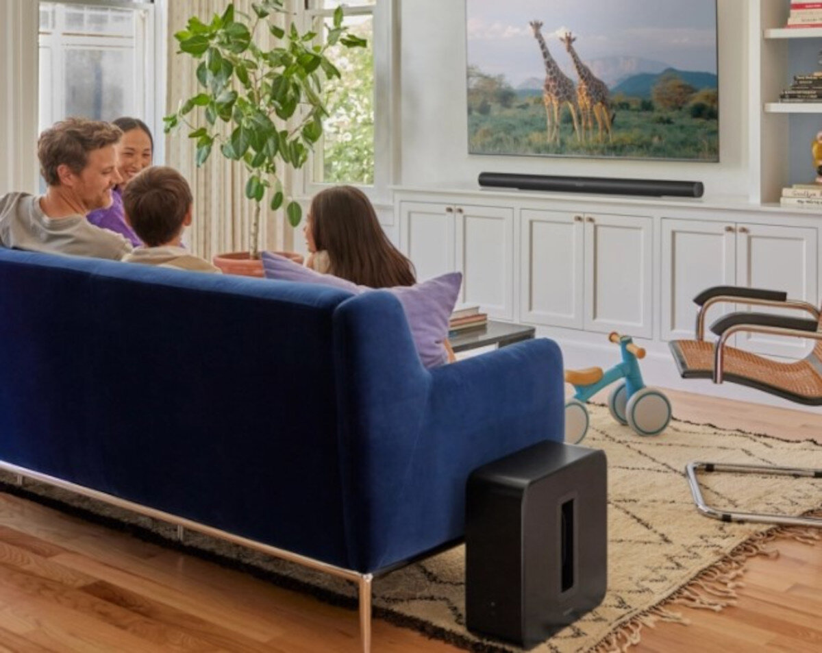 Subwoofer SONOS Sub 4 - Swoboda ustawienia w domu, Subwoofer stojący przy kanapie w salonie, ludzie siedzący na kanapie