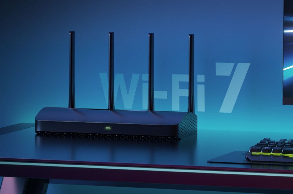 Router MERCUSYS MR27BE Router stojący na biurku obok klawiatury komputerowej, z dużym napisem 'Wi-Fi 7' widocznym w tle, podkreślającym standard pracy urządzenia