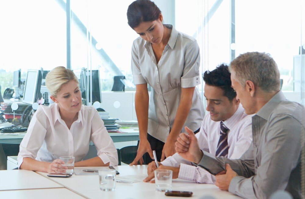 Laptop ASUS Chromebook Plus CB3402CVA Czworo osób w biurze podczas rozmowy przy stole. Jedna kobieta stoi pochylona nad pozostałą trójką, akumulator, czas pracy