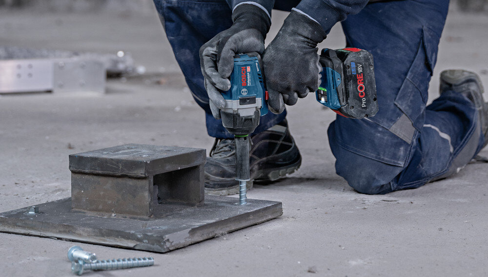 Klucz udarowy BOSCH GDS 18V-750 plac budowy osoba dokręca śruby w metalowych elementach dwa standardowe tryby pracy do śrub i nakrętek metalowych do wkrętów w drewnie ogranicza ryzyko złamania łbów wypadania elementów funkcja ABR automatycznie redukuje obroty po poluzowaniu