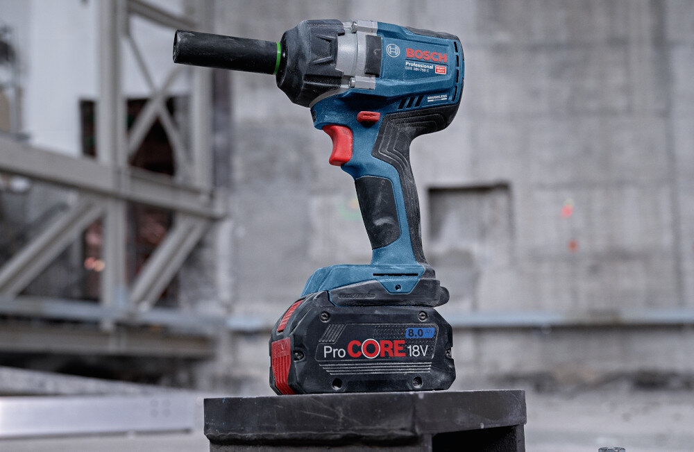 Klucz udarowy BOSCH GDS 18V-750 C 06019L9002 plac budowy klucz ustawiony na metalowym schodku w tle betonowy mur dla majsterkowiczów wszechstronne zastosowanie wydajność