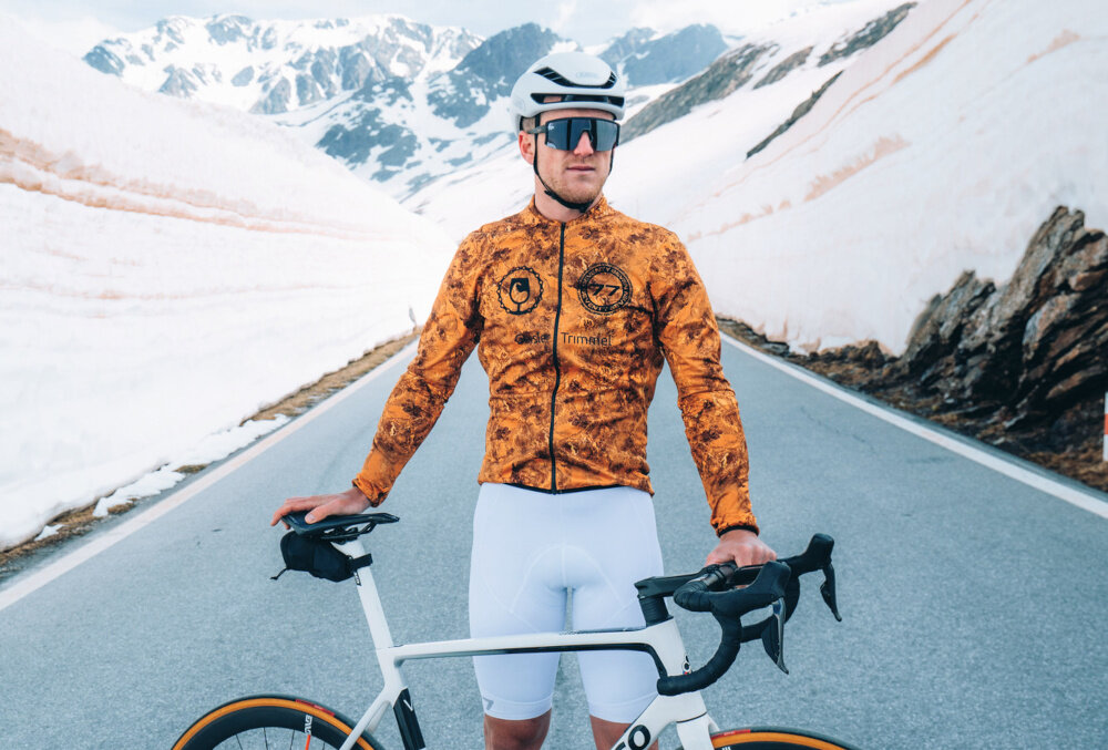 Kask rowerowy ABUS Gamechanger Polar Biało-czarny Szosowy rozmiar L, 59-62 cm krajobraz górski osoba zakłąda okulary osoba w kasku paski Flow Straps Pro ogranicza opór przepływu i hałas cienka górna część zapięcie na zatrzask miękkie poduszki mają mocowanie na rzepach przedni i tylny uchwyt na okulary