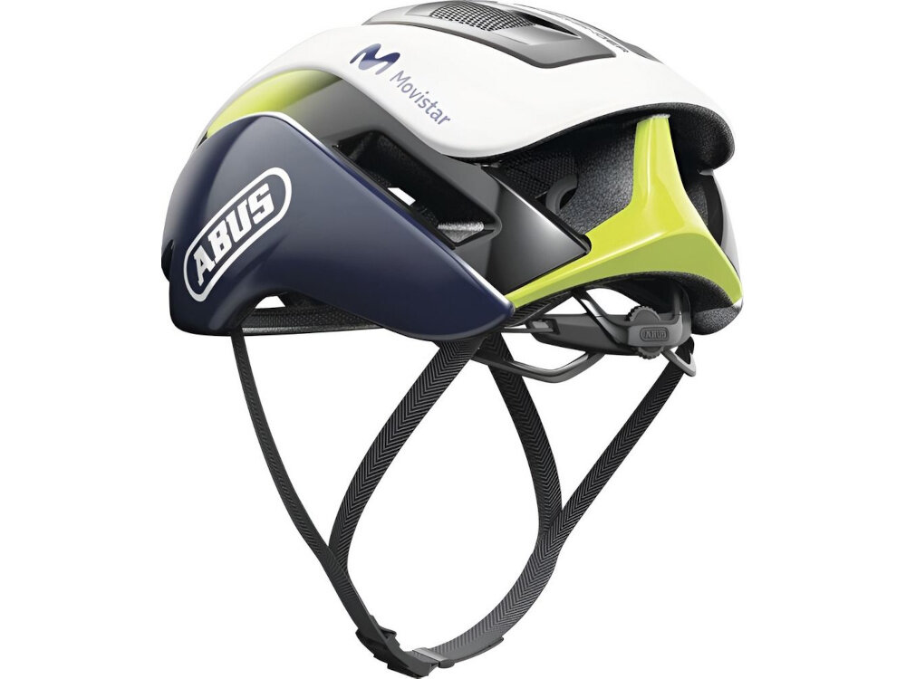 Kask rowerowy w kolorach czarno-białym z elementami zielonymi i granatowymi, z widocznymi napisami \'ABUS\' i \'Movistar\'.