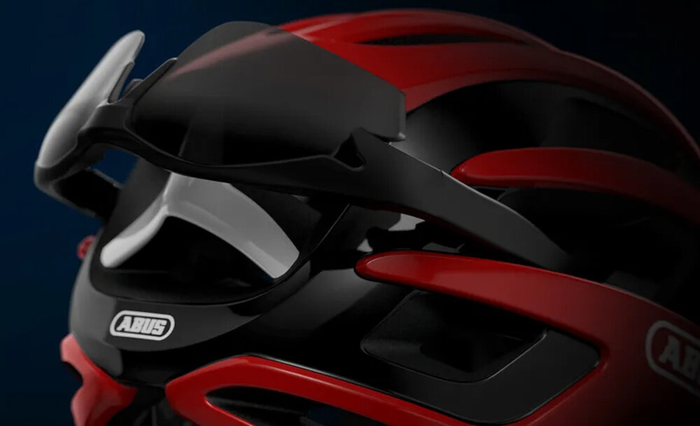 Kask rowerowy ABUS AirBreaker Performancer Performance Czerwony Szosowy rozmiar L ciemne tło zbliżenie na tył kasku na kasku założone okulary wbudowany uchwyt AirPort stabilne i bezpieczne przymocowanie okularów do tylnej części kasku specjalne prowadzenie zauszników zapobiega ich przesuwaniu się szybki dostęp