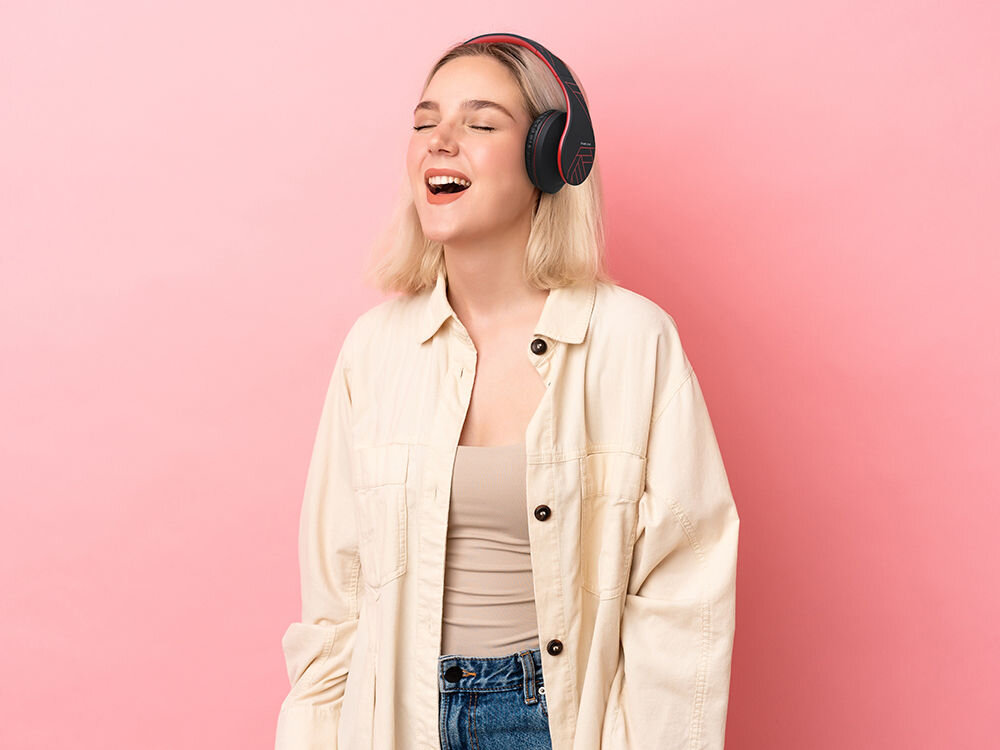 Słuchawki PowerLocus P2 - Styl, komfort i energia, osoba z założonymi słuchawkami nausznymi na brzoskwiniowym tle