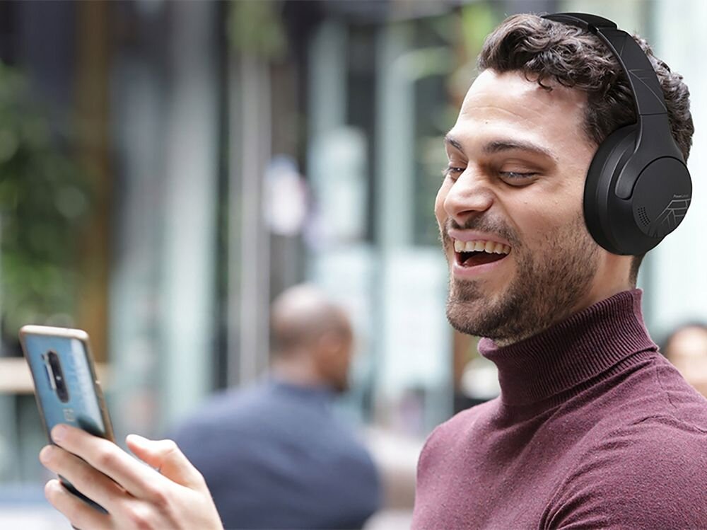 Słuchawki nauszne POWERLOCUS P3 tryb gamingowy niskie opóźnienia, osoba z załozonymi słuchawkami nausznymi z telefonem w ręku