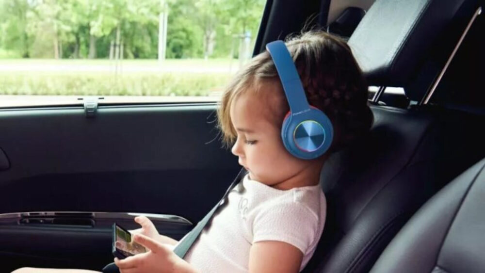 słuchawki nauszne POWERLOCUS Pled - Rozmowy w trybie handsfree, dziecko trzymające w ręku smartfona z założonymi słuchawkami, dziecko siedzące w samochodzie