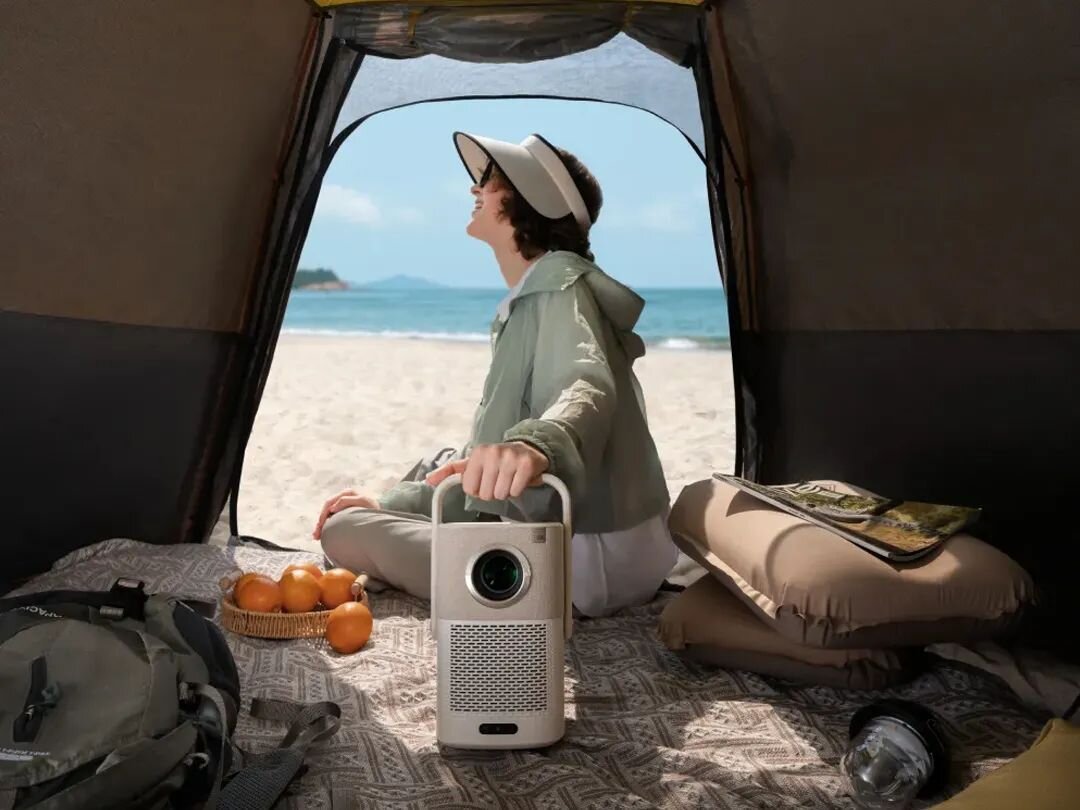 Projektor YABER T2 Plus - Domowe kino premium, osoba trzymająca projektor za uchwyt w namiocie