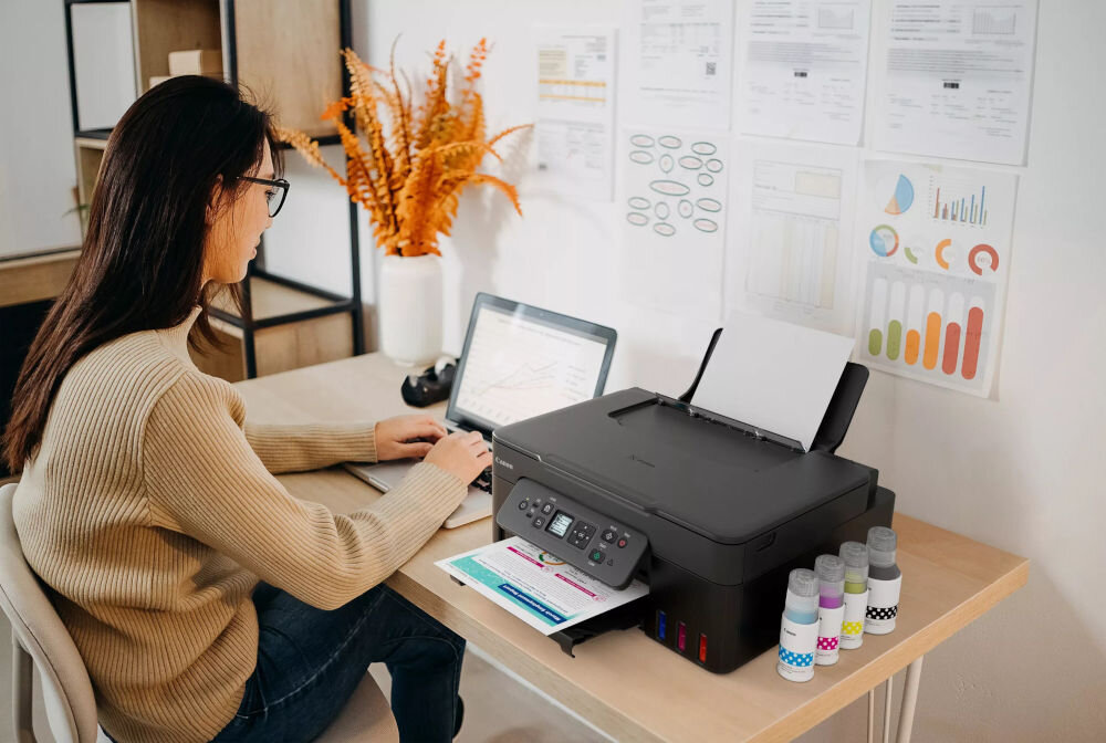 Urządzenie wielofunkcyjne CANON Pixma G3480 Druk w kolorze, Automatyczny druk dwustronny, Wi-Fi  prezentacja urządzenia na biurku w biurze przy biurku siedząca kobieta