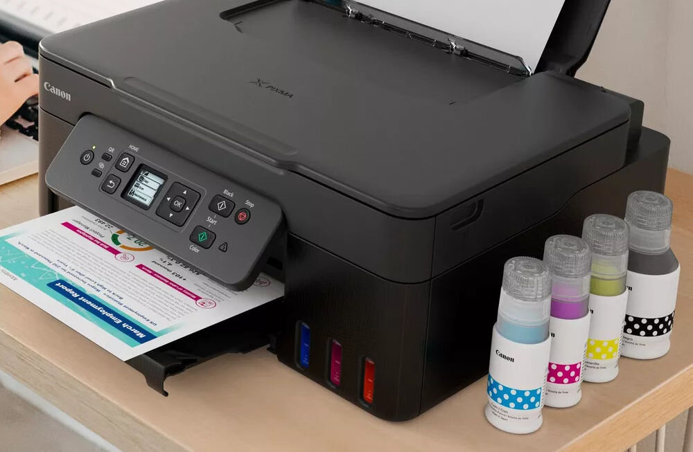 Urządzenie wielofunkcyjne CANON Pixma G3480 Druk w kolorze, Automatyczny druk dwustronny, Wi-Fi  prezentacja urządzenia na biurku obok butelki z tuszem tusze startowe w zestawie