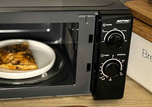 Zbliżenie na otwartą kuchenkę mikrofalową MPM-20-KMM-12, w której znajduje się żywność.