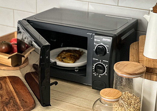 Kuchenka mikrofalowa MPM-20-KMM-12 na kuchennym blacie z otwartymi drzwiami, w środku niej żywność.