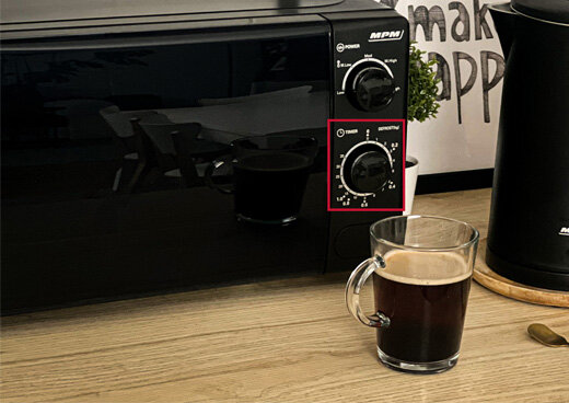 Zbliżenie na pokrętła kuchenki mikrofalowej MPM-20-KMM-12 ustawionej na kuchennym blacie.